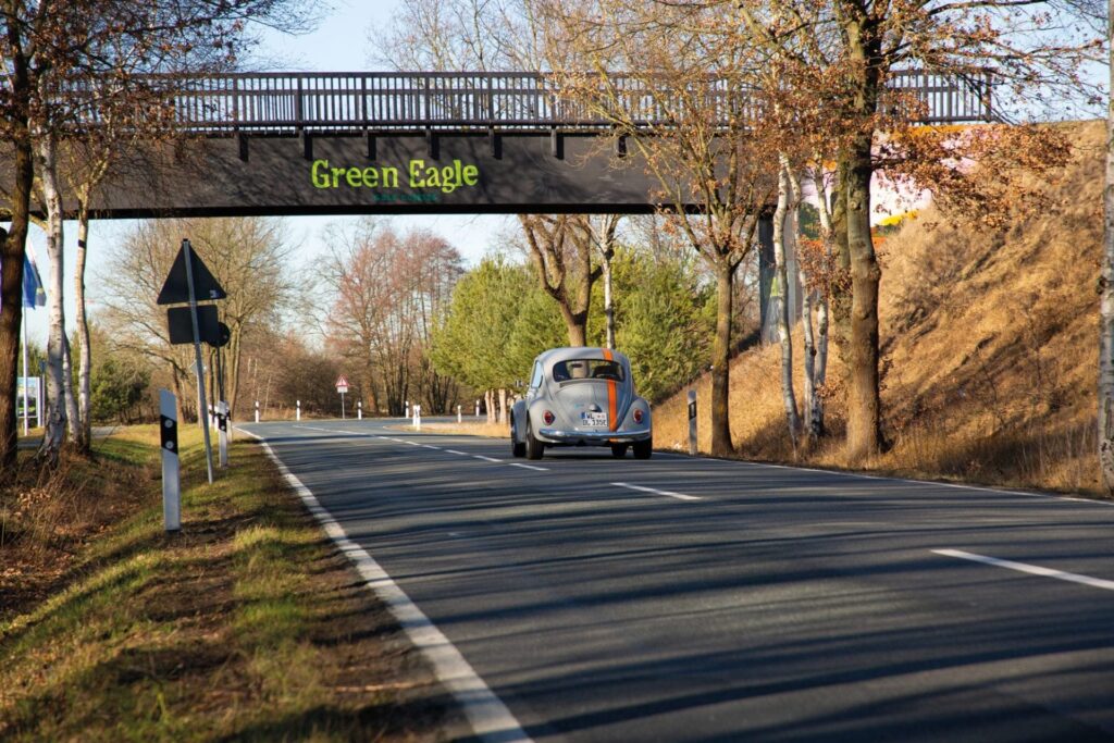 Oldtimer (elektrisch unter alter Haube) fährt auf einer Landstraße.