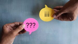 Zwei Hände zeigen Notizzettel mit Frage- und Ausrufezeichen