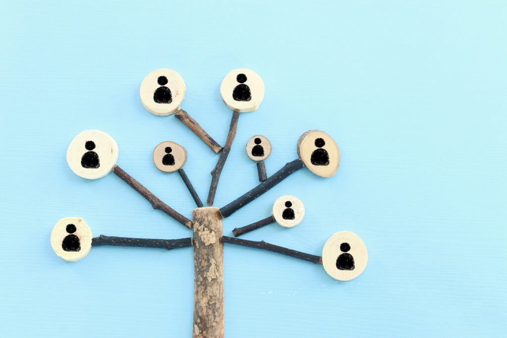 Baum aus Holz, dessen Äste zu Symbolen von Menschen führen und damit ein Netzwerk aus miteinander verbundenen Personen darstellen